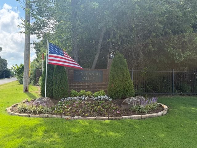 American flag flying beside a neighborhood entrance sign